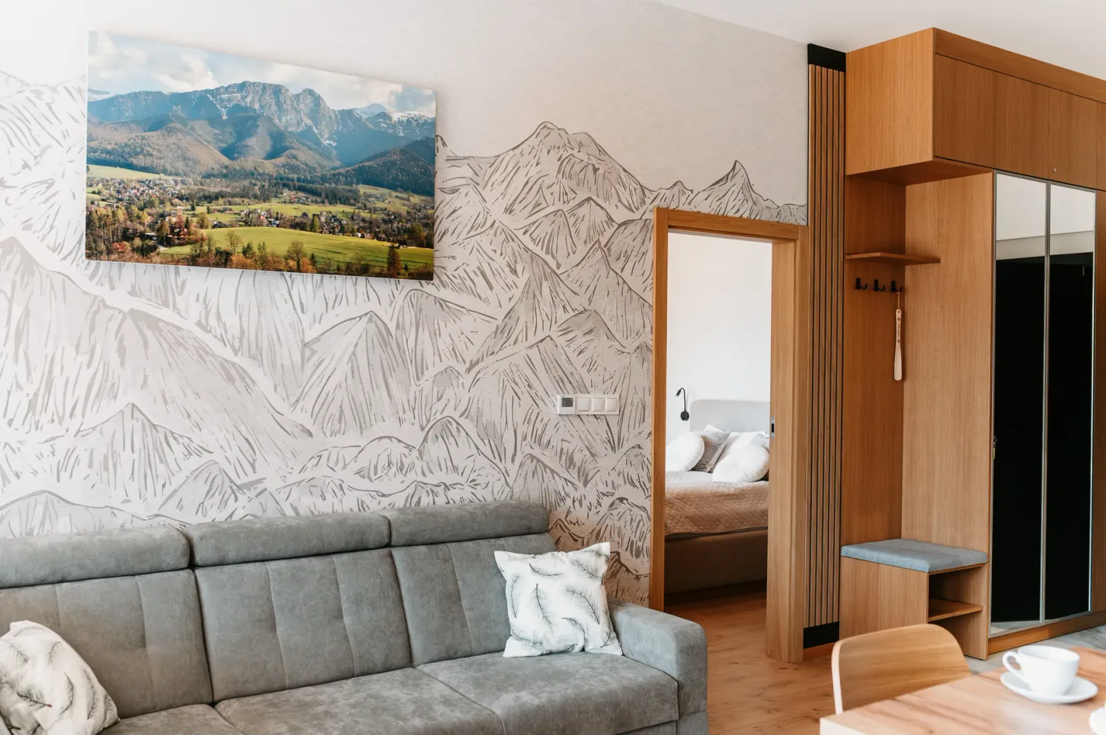 Salon z tapetą w góry, zabudową przy wejściu i widokiem na sypialnię