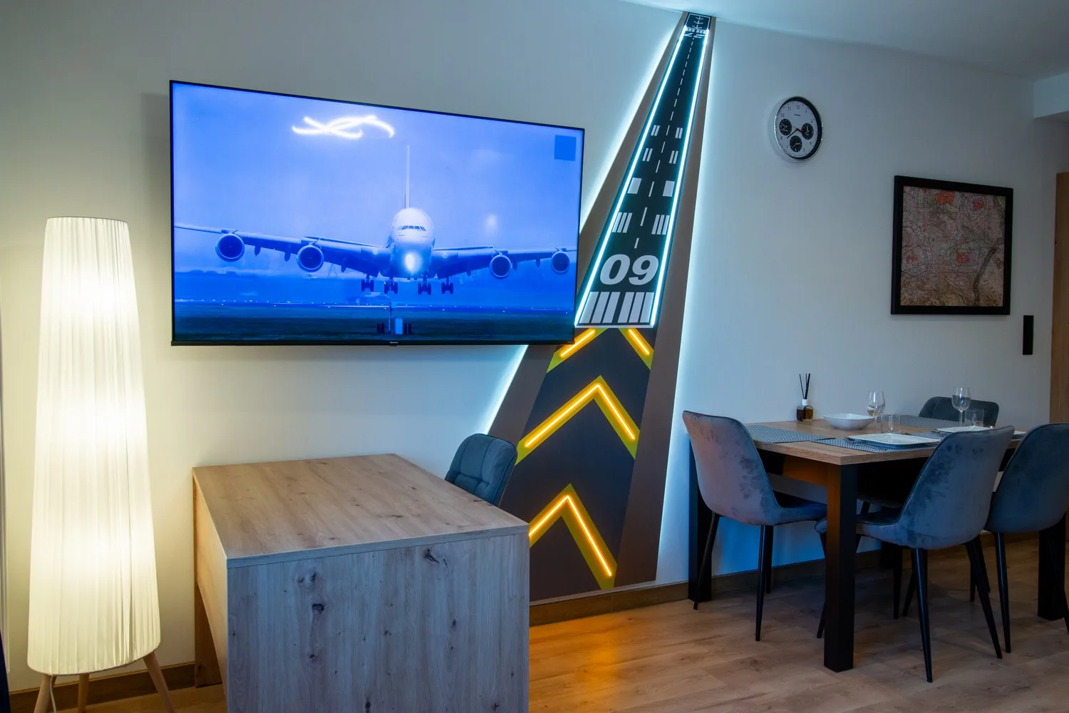 Wiszący telewizor na ścianie z grafiką pasa startowego i oświetleniem LED – mocny akcent stylistyczny wnętrza
