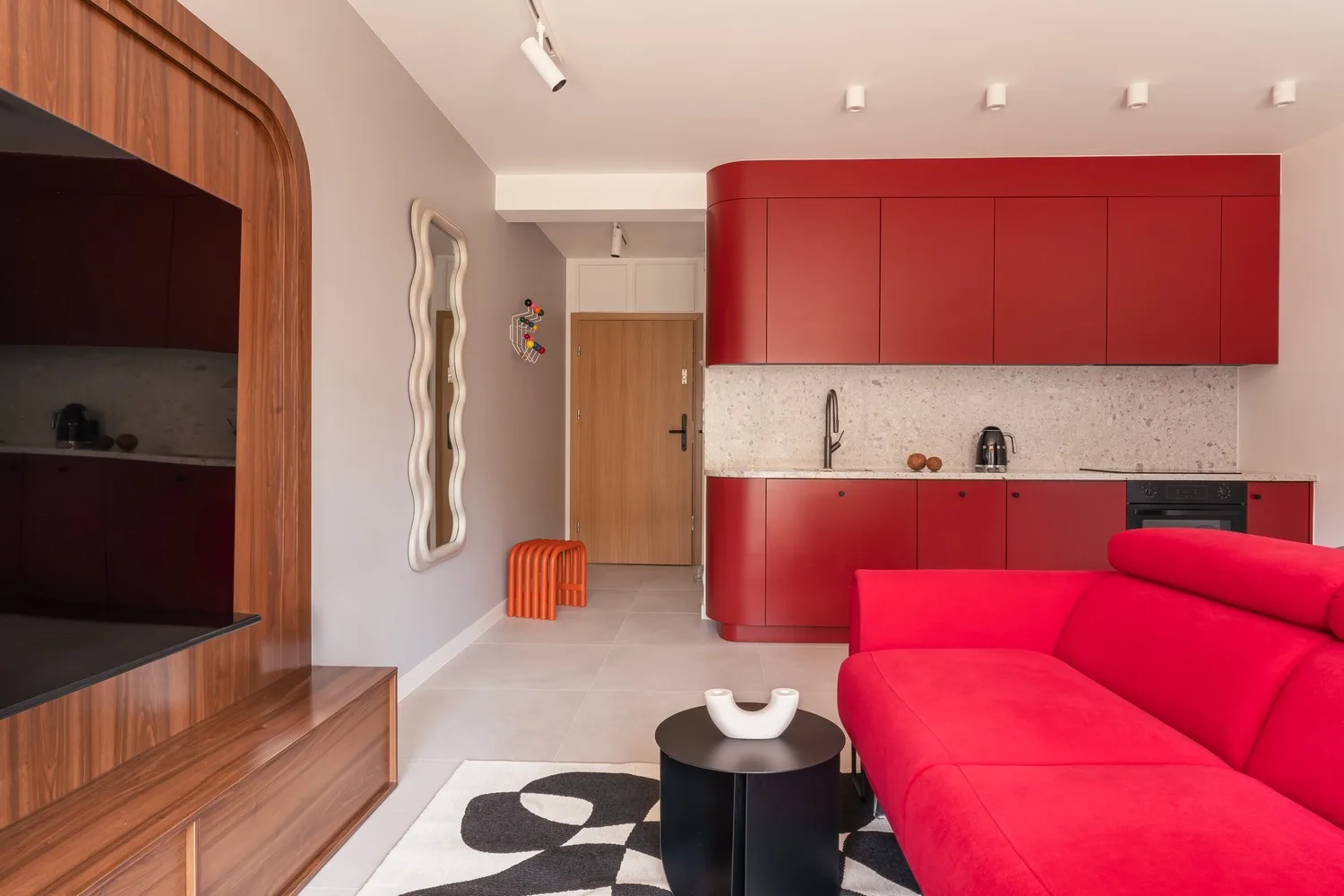 Przestrzeń dzienna z jaskrawoczerwoną sofą i nowoczesną zabudową kuchenną w apartamencie Kopenhaga
