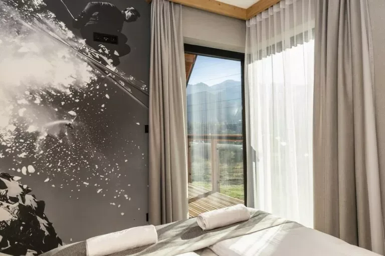 Szymaszkowa 7, Apartament 12 - Czarno-biała grafika narciarza na ścianie sypialni z wyjściem na balkon
