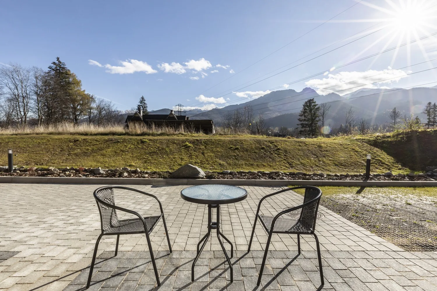 Taras Apartamentu 0.3, – stolik i dwa krzesła ogrodowe z panoramicznym widokiem na Tatry