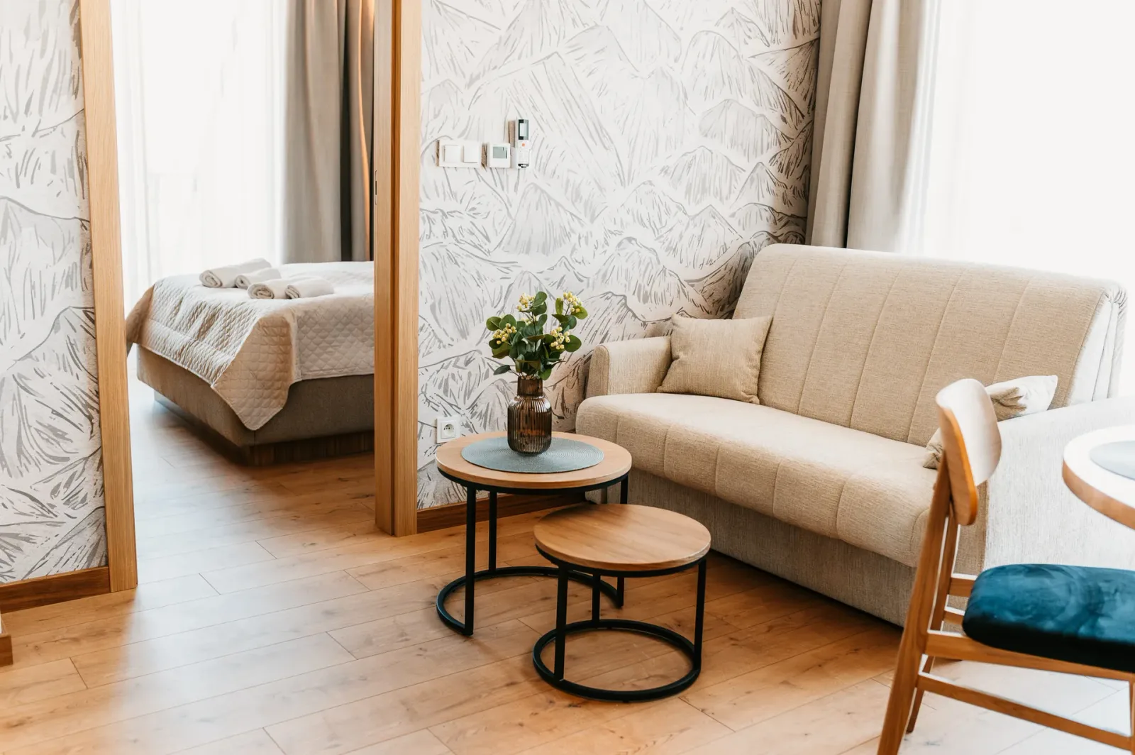 Salon z sofą, stolikami i przejściem do sypialni