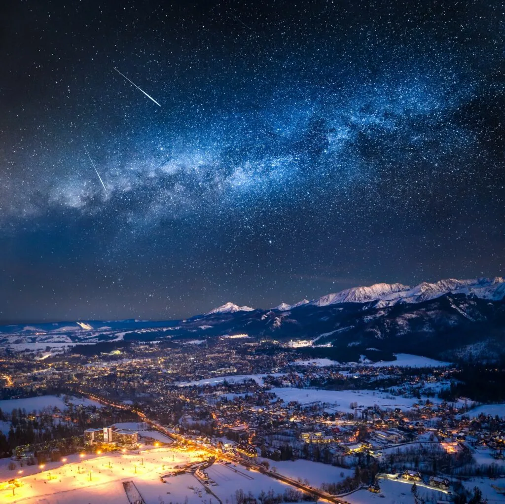 Panoramiczny widok na Zakopane nocą z gwiaździstym niebem nad Tatrami
