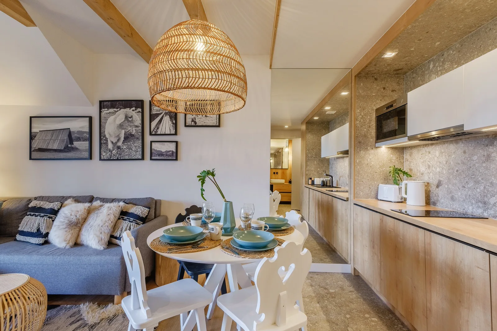 Apartament Relax, Villa Antałówka Zakopane – drewnopodobna kuchnia, biały stół z krzesłami i kanapa w strefie dziennej